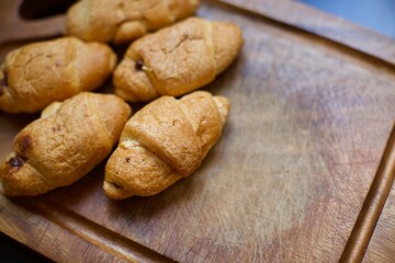 Close up view of homemade croissants. A few pieces of croissants on the serving board. Blurry background.
