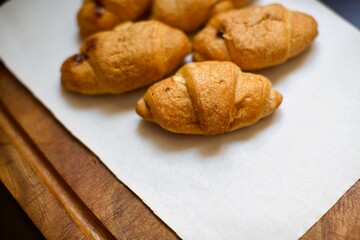 Close up view of homemade croissants. A few pieces of croissants on the serving board. Blurry background.