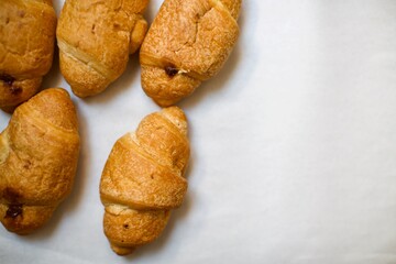 Close up view of homemade croissants. A few pieces of croissants on the serving board. Blurry background.