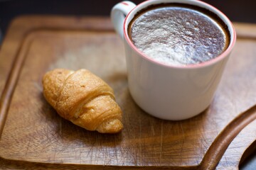 Aerial view of croissant and glass of black coffee. Blurry and black background. 