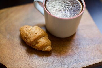 Aerial view of croissant and glass of black coffee. Blurry and black background. 