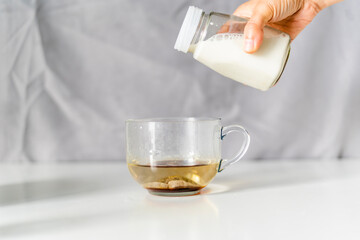 Pouring milk on a cup of black tea