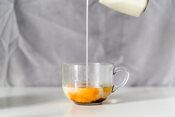 Pouring milk on a cup of black tea
