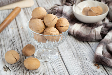 closed walnuts in dishes on a light wooden background, textiles, cutting Board