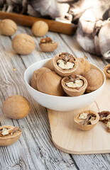 closed and split walnuts in dishes on a light wooden background, textiles, cutting Board