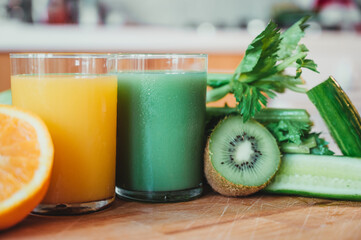 Orange juice with fresh oranges in the foreground and green juice in the background