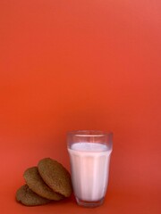 Glass of milk with brown oatmeal cookies on a beard background