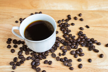 Black coffee placed on a wooden table with coffee beans.