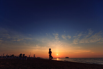 sea and sun set. girl silhouette in boater on the sandy beach ad