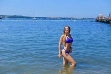 Young pretty sexy woman in blue swimsuit and sunglasses standing