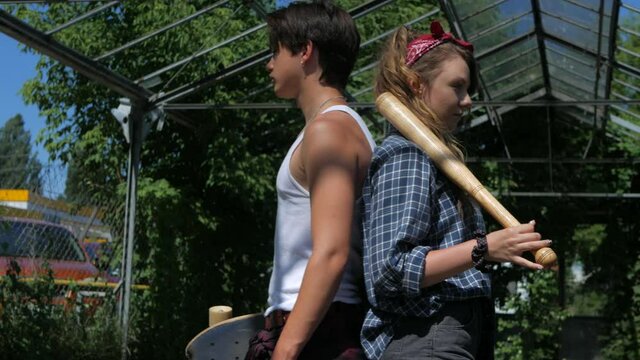 Serious guy and girl posing for the camera. Fashionable models hug. Couple in love. Old school, seit, bats, hooligans. Original young couple in love. Portrait.
