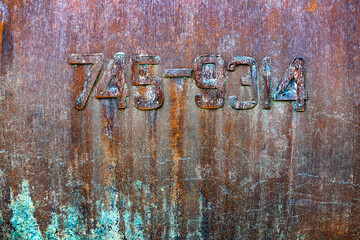 Texture of old painted metal wall with a serial number. Corrosion and cracked rusty surface