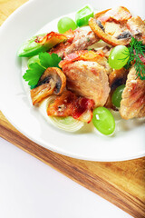 Pork with mushrooms, grapes, leek and parsley on wooden stand. White background. High key. Selective focus.