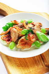 Pork with mushrooms, grapes, leek and parsley on wooden stand. White background. High key. Selective focus.