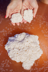 Crystals of salt in hand on a pink lake