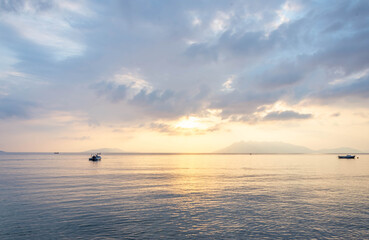 Fototapeta premium scenic view of cloudy sky, sea and fishing boat at sunset