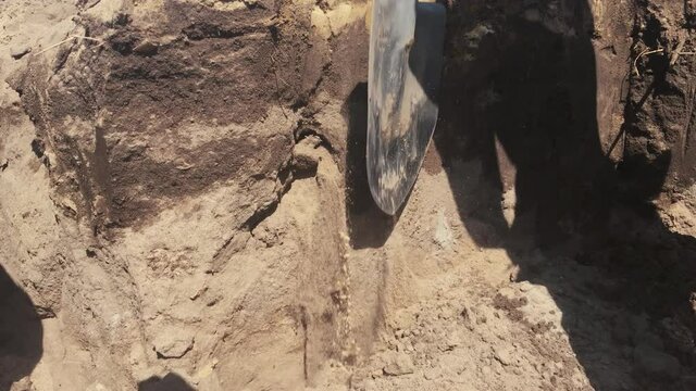 man worker digs a hole in the ground with a shovel and puts it in a cart. grave digger digs grave. concept work construction. lifestyle male rough work slave