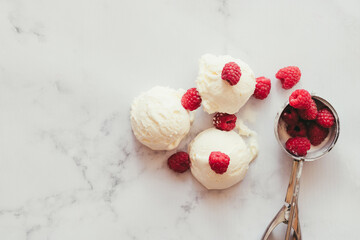 Fototapeta na wymiar Melting balls of vanilla ice cream on a marble table with raspberries.