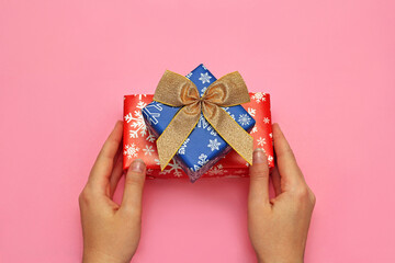 a woman holds a gift box on a pink background. christmas 