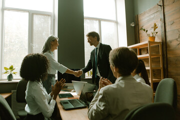 Handshake of leaders to the applause of colleagues. Business people shaking hands with each other. Team work in office. Toned image.