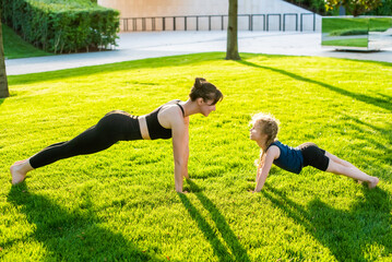 woman and child do yoga in the park. lotus position. summer, sun, mother and daughter, health....