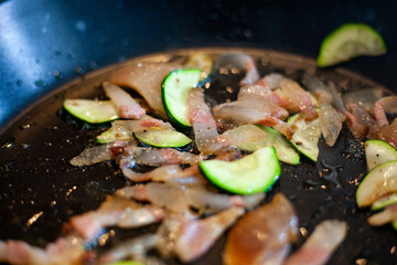 Preparazione per spaghetti con zucchini e pancetta saltati in padella.