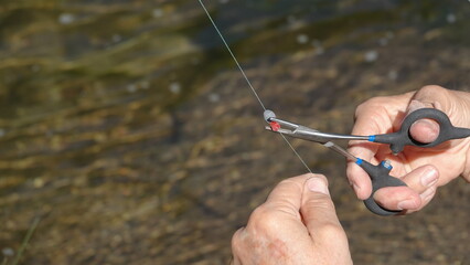 Close up of a fisherman's hands attaching a line bead to fishing line 