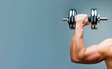 Arm attractive athletic man with dumbbells with copy space