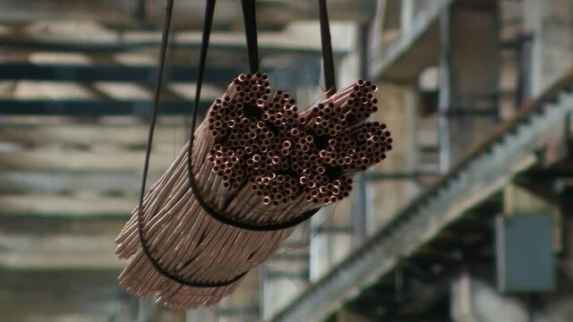 Copper Pipes in the Air are Raised by a Crane Beautiful Shining Metal in Factory of Metal Production Brass Tubes
