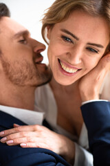 Happy passionate couple in love touching, kissing and huging. Focus on female happy eyes and hand in foreground. Enjoyment concept. Close up shot.