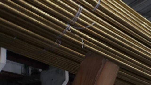 A Crane is Loading Huge Heap of Copper Tubes in Factory of Metal Production Hard Work on Industrial Line Close Up