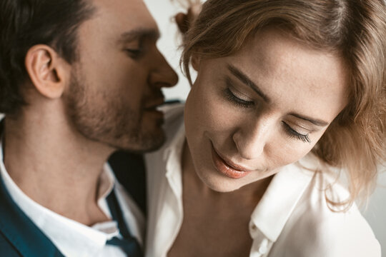 Sexy couple of business people in love. Close up portrait. Man going to kiss female neck. Selective focus on happy smiling female face in foreground.