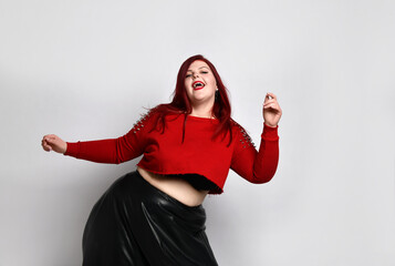 Obese ginger lady in red spiked top, black bra and leather skirt. She is dancing, posing isolated...