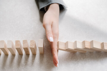 businessman hand stops falling wooden blocks