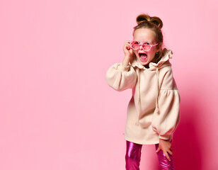 naughty girl with a funny hairstyle, dressed in a pink sweatshirt, screamed, angrily plugging...