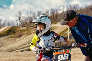 kids riding at motobike, junior competition on motorcycle. Coach gives instructions to his young rider