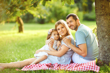Happy family is hugging while sitting in the park.