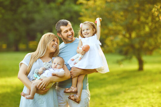 Happy male and female playing with children outside in the park