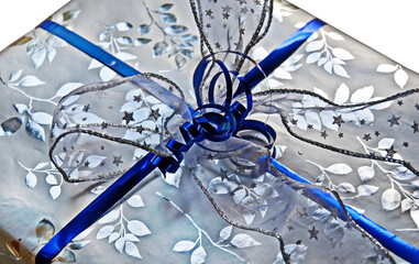 This is a closeup of a silver and royal or cobalt blue wrapped gift, isolated on a white background.  This present could be used for many special occasions and holidays.