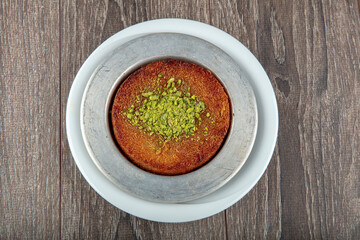 Turkish dessert kunefe, kunafa, kadayif with pistachio powder and cheese hot eaten a sweet.