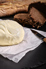 Loaf of bread with butter and knife. Dark background, side view