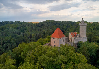 Fototapeta na wymiar Aerial view on a medieval castle, Kokorin. Fortified palace with a tower and a wall standing on a hill covered by pines.Touristic spot. Castles in the Central Bohemian Region, Czech republic.
