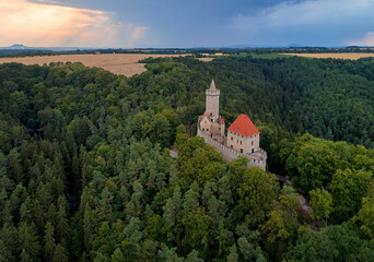 Fototapeta premium Aerial view on a medieval castle, Kokorin. Fortified palace with a tower and a wall standing on a hill covered by pines.Touristic spot. Castles in the Central Bohemian Region, Czech republic.