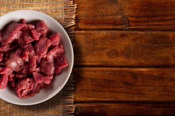 White bowl with meat raw on wood background. Top view.