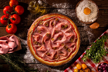 Brazilian pizza with mortadella and green olive. Top view on wood background, close up. Traditional Brazilian Pizza