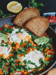 Shakshuka with eggs, tomatoes, bell pepper and parsley in a pan. Shakshuka is a traditional Israeli food.