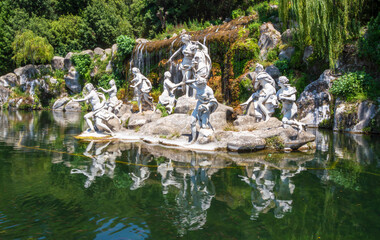 Fototapeta na wymiar Group of marble statues decorating pond with small cascade in Italy
