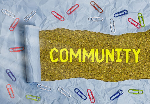 Conceptual hand writing showing Community. Concept meaning group of showing with a common characteristics living together Rolled ripped torn cardboard above a wooden classic table