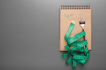 A fork wrapped around a tape measure, a crafting pad, on a neutral background. Minimalistic concept. The balance between nutrition and sport. Planning a diet. Healthy lifestyle. Space for text. 