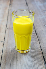Golden milk in a glass cup on a wooden background